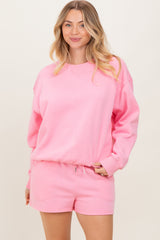 woman wearing a pink oversized sweatshirt and matching shorts