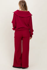 woman wearing a maroon wide-leg pant set with a large collar detail on the top, viewed from the back