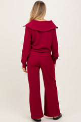 woman wearing a burgundy maternity ribbed top with a wide collar and matching wide-leg pants, showing her back