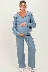 woman wearing a light blue maternity tracksuit with a zip-up top and wide-leg pants, showcasing her baby bump