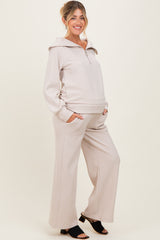 woman wearing a beige maternity lounge set with a zip-up hooded top and wide-leg pants, showcasing a baby bump