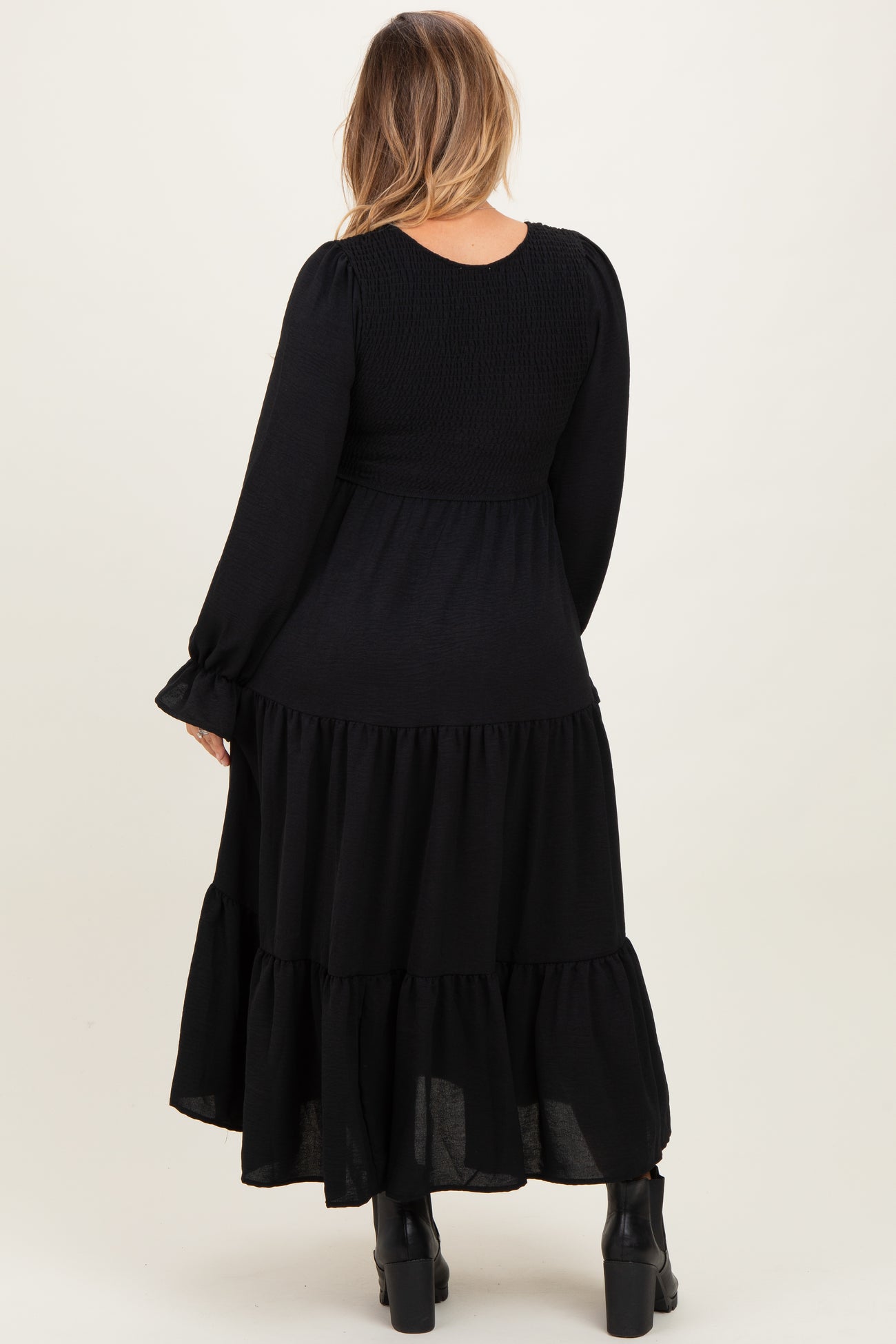 woman wearing a black maternity plus tiered maxi dress with long sleeves and smocked bodice, showing her back
