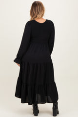 woman wearing a black maternity plus tiered maxi dress with long sleeves and smocked bodice, showing her back