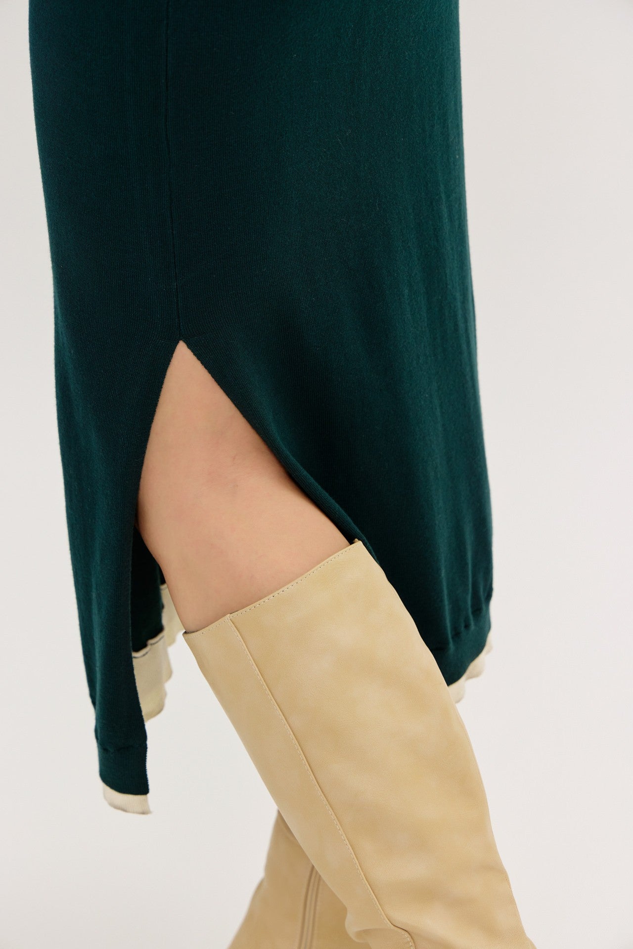 green midi dress with side slit and model wearing beige knee-high boots