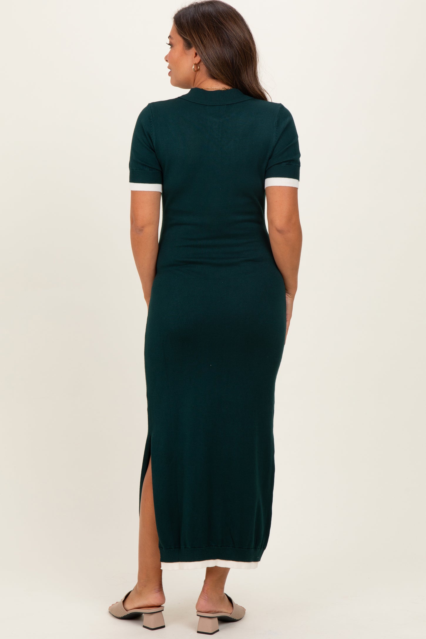 woman wearing a dark green maternity maxi dress with short sleeves and side slits, viewed from the back