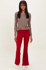 woman wearing a brown long sleeve henley top and red flared pants with white sneakers