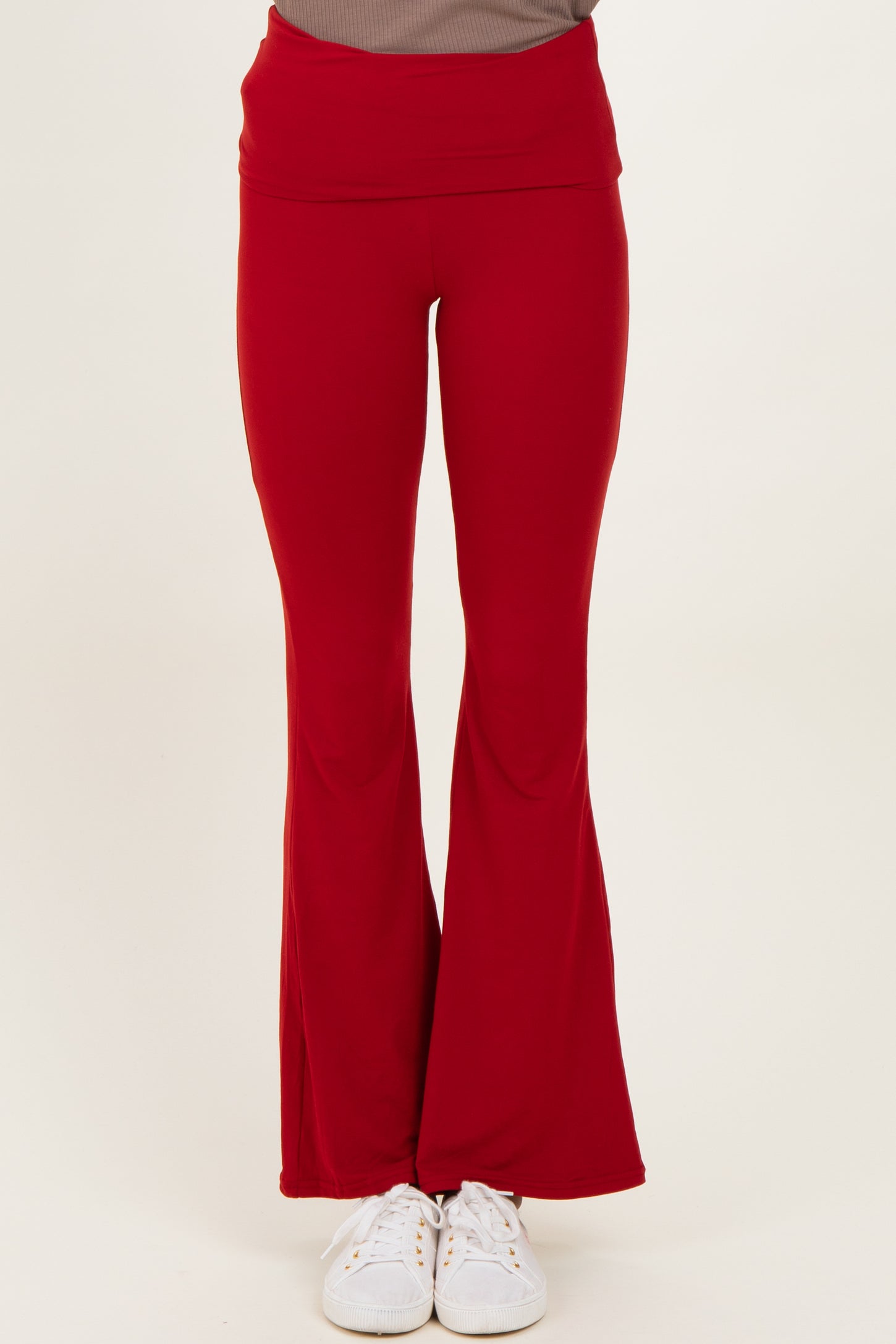 woman wearing red flared yoga pants with a high waistband and white sneakers