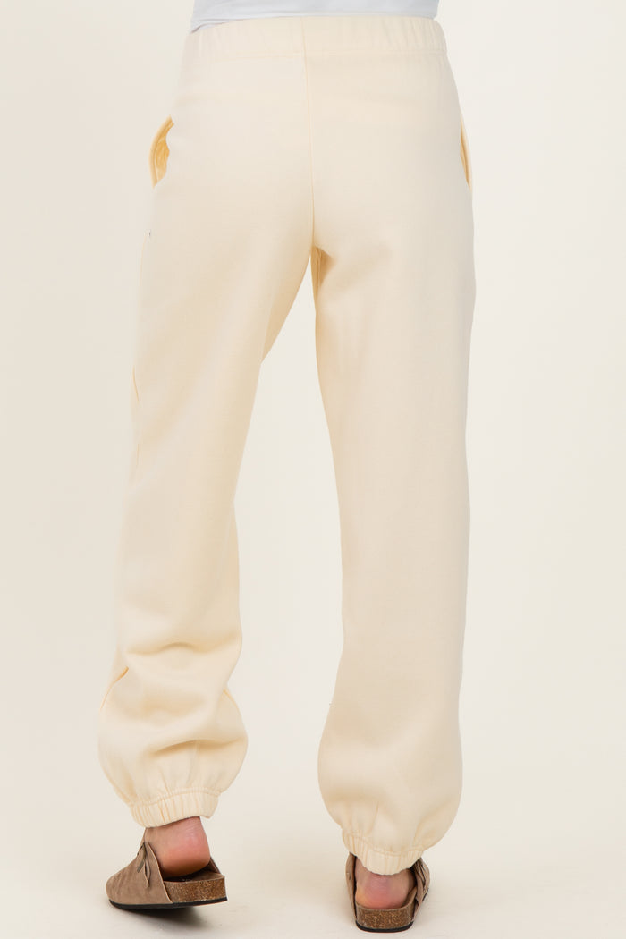 woman wearing cream maternity jogger pants, showing the back view with elastic drawstring at the waist