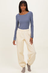 woman wearing a long sleeve blue top and cream-colored tapered sweatpants with cuffs at the ankles