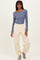 woman wearing a long sleeve blue top and cream-colored tapered sweatpants with cuffs at the ankles