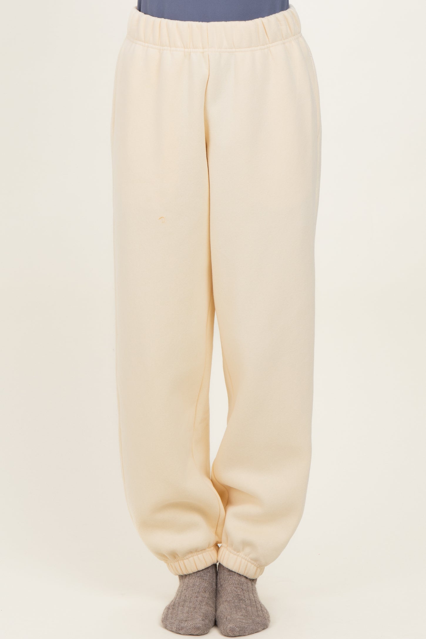 woman wearing cream colored relaxed fit sweatpants with an elastic waistband and cuffed hems