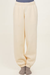 woman wearing cream colored relaxed fit sweatpants with an elastic waistband and cuffed hems