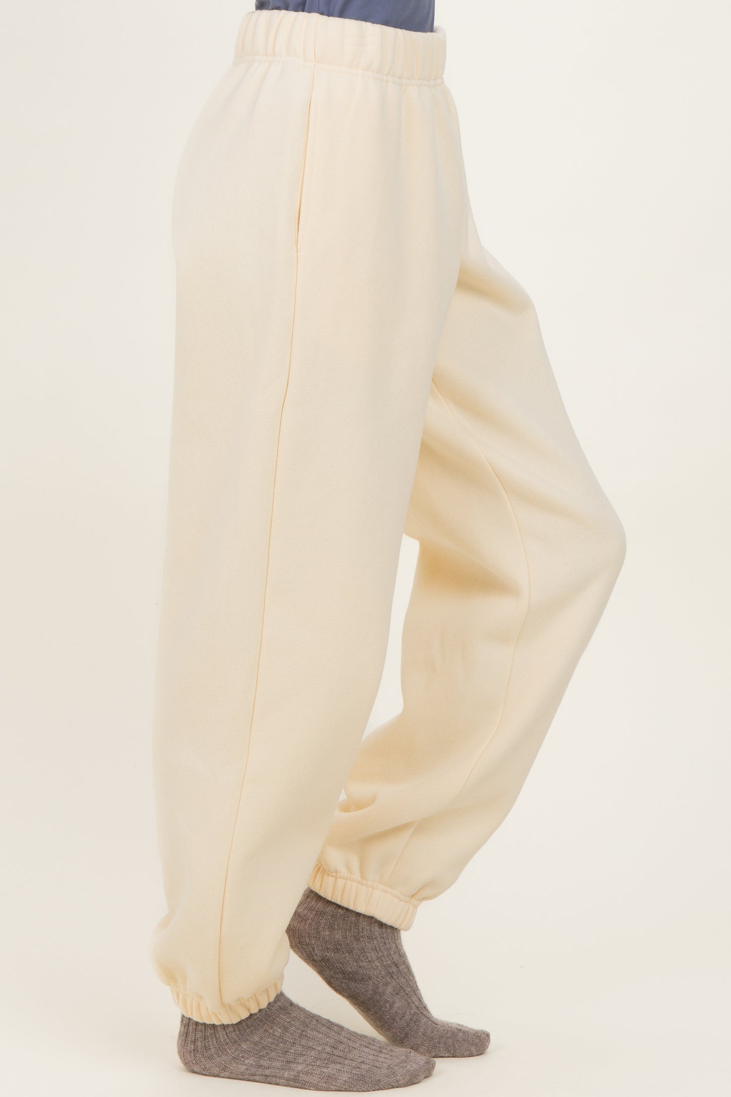 woman wearing cream-colored sweatpants with elastic waistband and cuffs, paired with gray socks