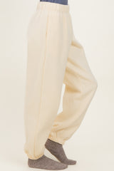 woman wearing cream-colored sweatpants with elastic waistband and cuffs, paired with gray socks