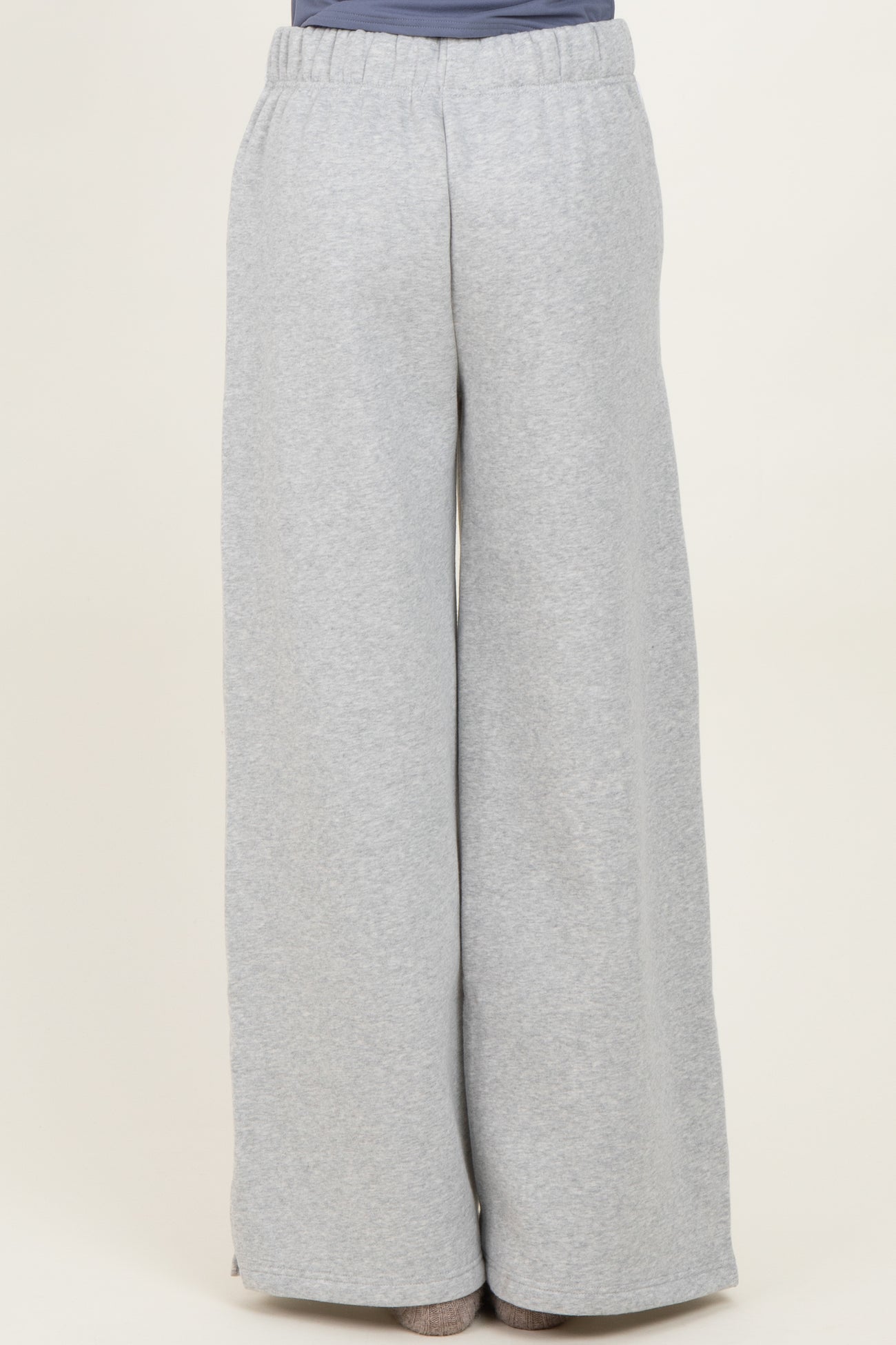 woman wearing light grey wide-leg sweatpants with an elastic waistband, seen from the back