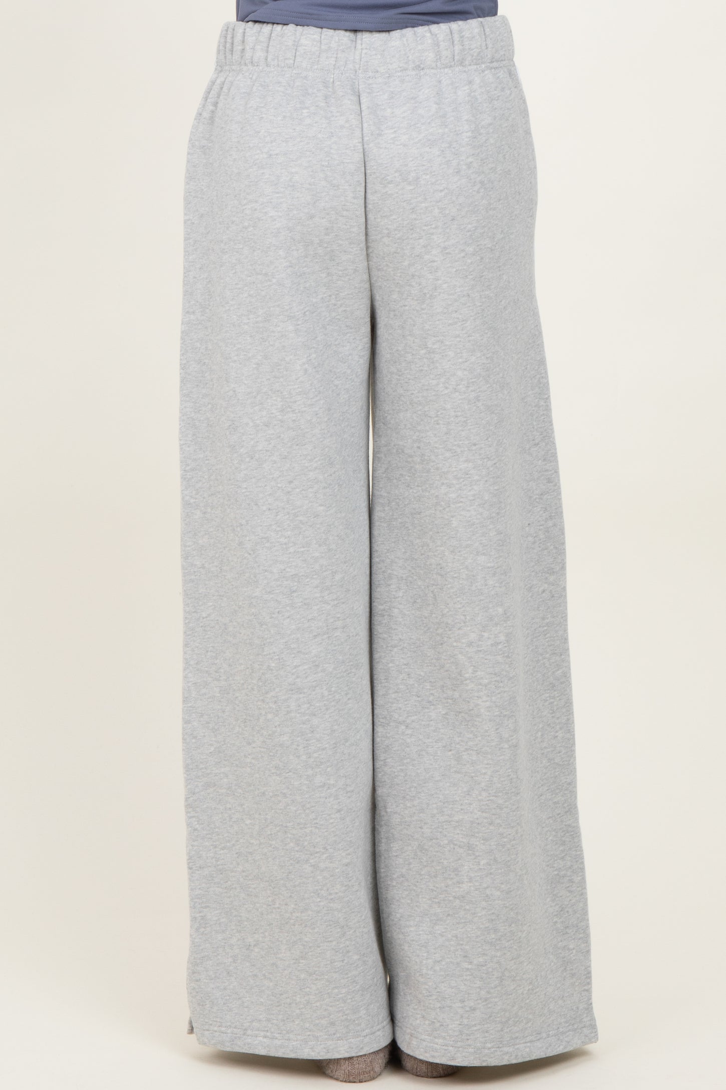 woman wearing light grey wide-leg sweatpants with an elastic waistband, seen from the back
