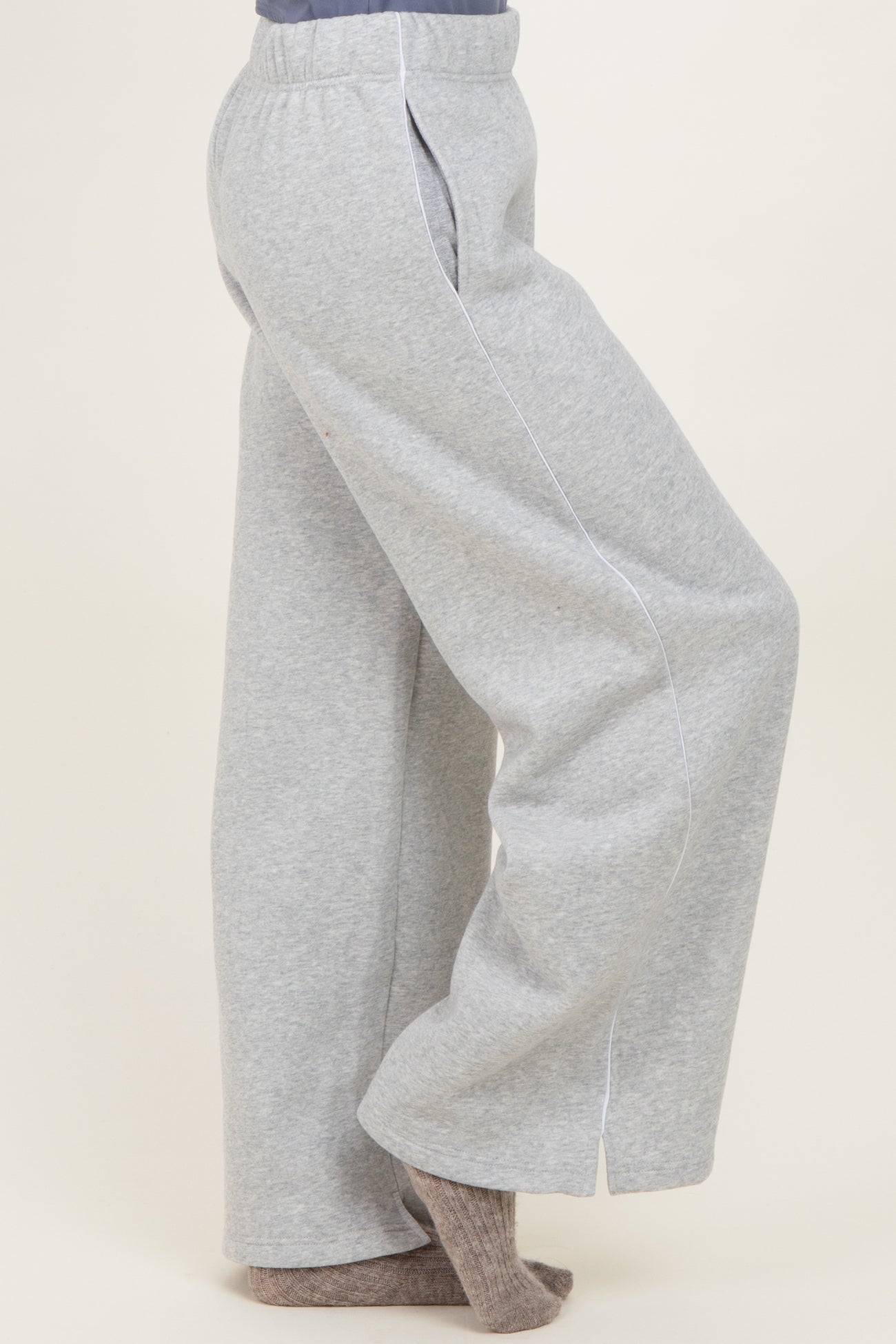 woman wearing gray wide-leg sweatpants with white piping details and a relaxed fit