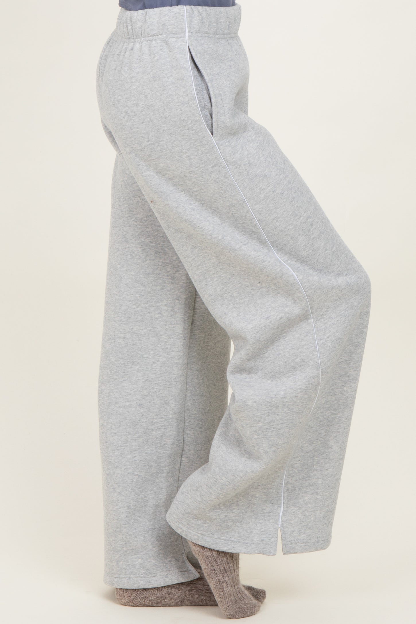 woman wearing gray wide-leg sweatpants with white piping details and a relaxed fit