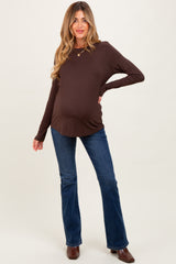 woman wearing a brown long sleeve maternity top and blue flared jeans with a visible baby bump
