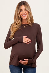 woman wearing a dark brown long sleeve maternity top and holding her baby bump