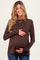 woman wearing a dark brown long sleeve maternity top and holding her baby bump