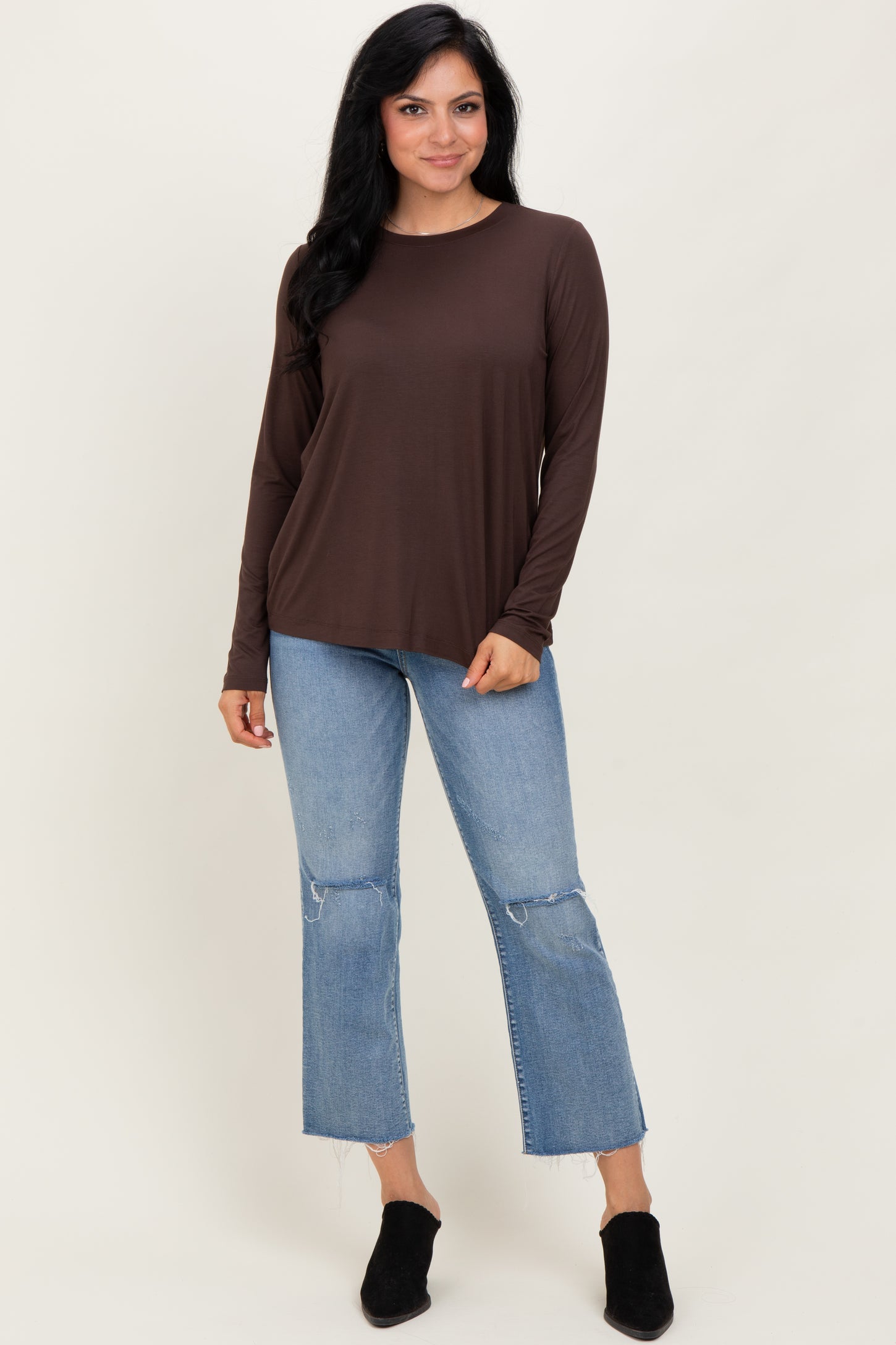 woman wearing a brown long sleeve top with a relaxed fit and distressed light wash jeans