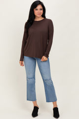 woman wearing a brown long sleeve top with a relaxed fit and distressed light wash jeans