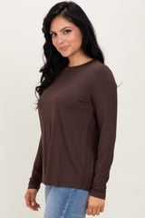 woman wearing a brown long sleeve top with a relaxed fit and side seams, paired with light blue jeans