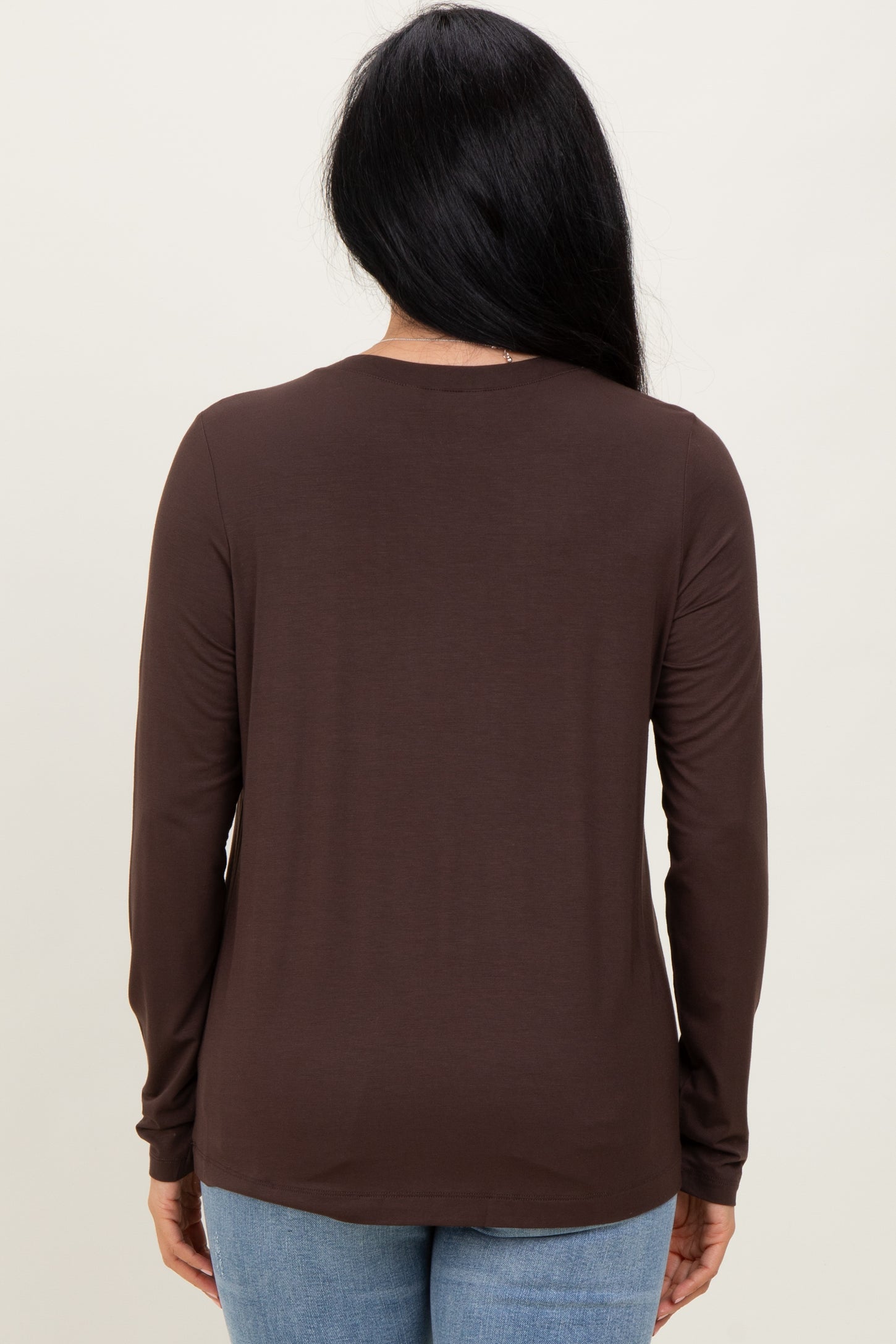 woman wearing a brown long sleeve top, viewed from the back, paired with light blue jeans