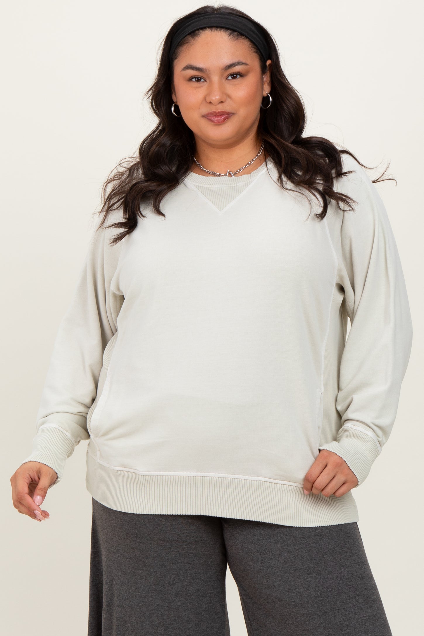 woman wearing a light gray plus size sweatshirt with a v-neck and long sleeves, paired with dark gray pants