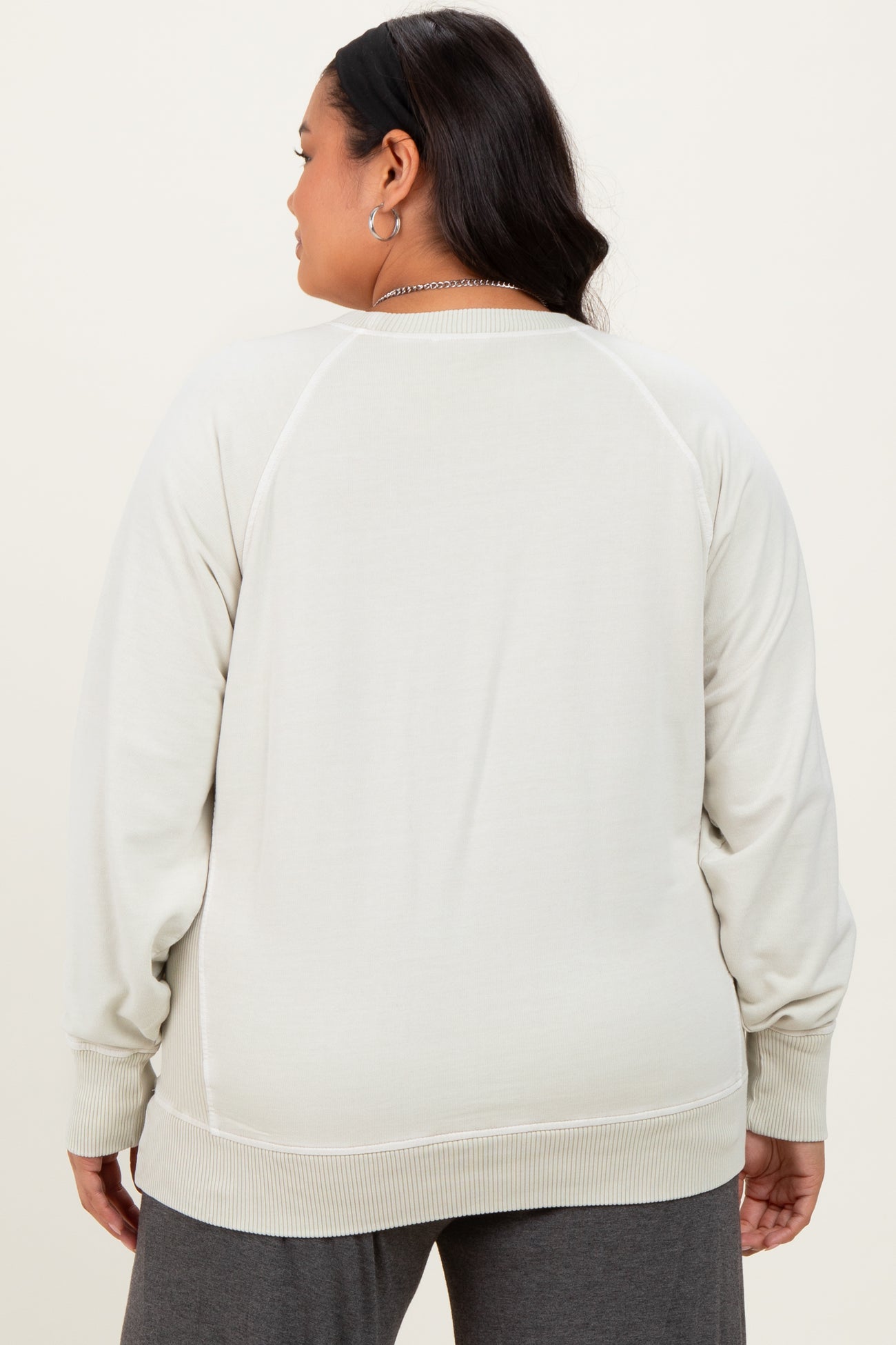 woman wearing a light gray plus size sweatshirt with a relaxed fit and ribbed cuffs, viewed from the back