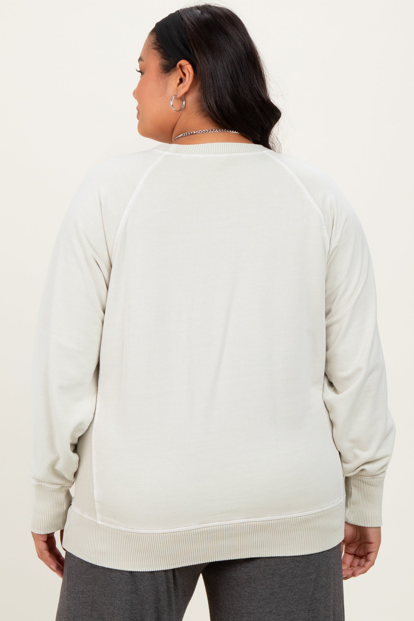 woman wearing a light gray plus size sweatshirt with a relaxed fit and ribbed cuffs, viewed from the back