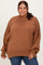 woman wearing an oversized rust brown sweater with a high neck and long sleeves paired with denim jeans