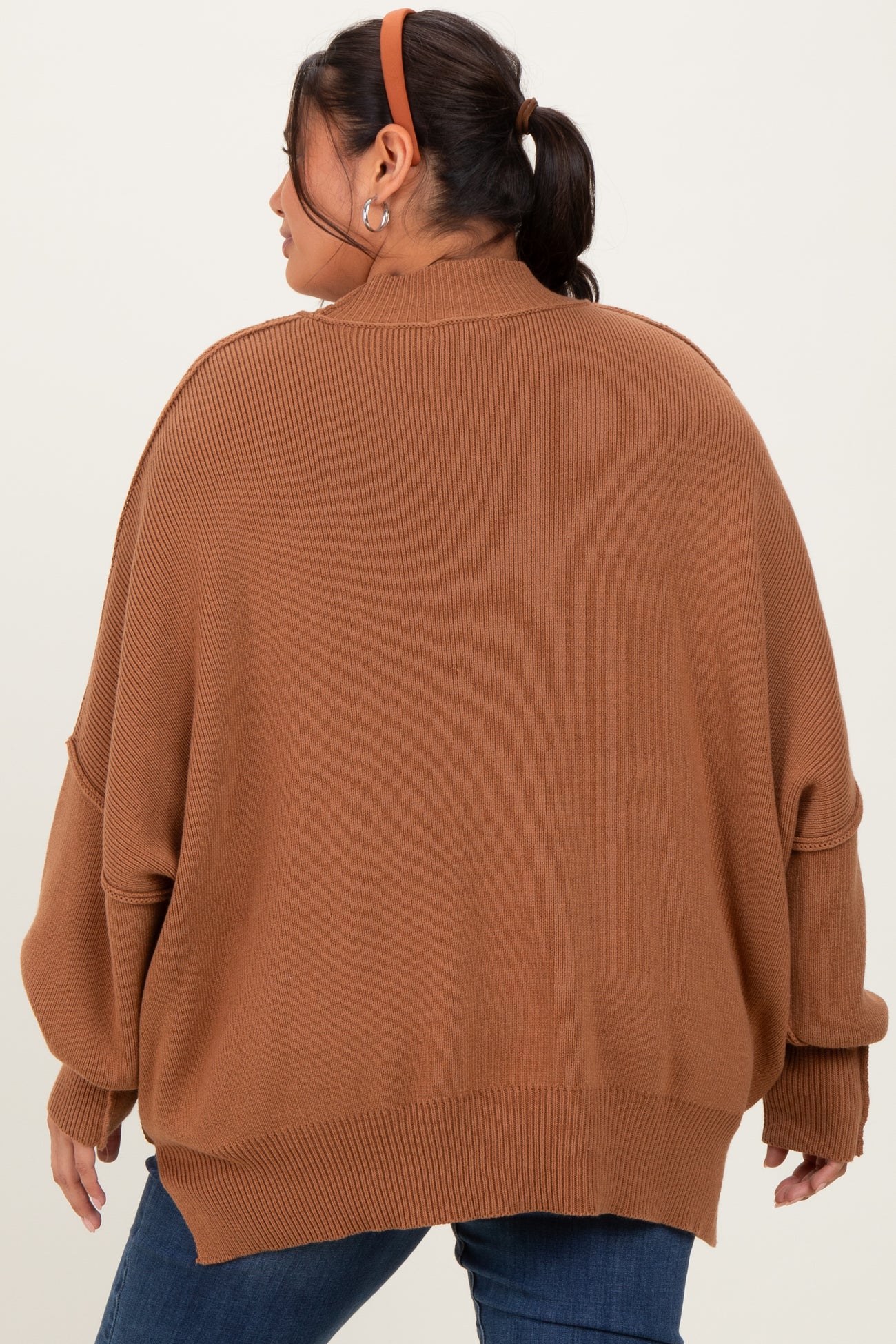 woman wearing a brown oversized sweater with a ribbed texture and dropped shoulder seams, viewed from the back