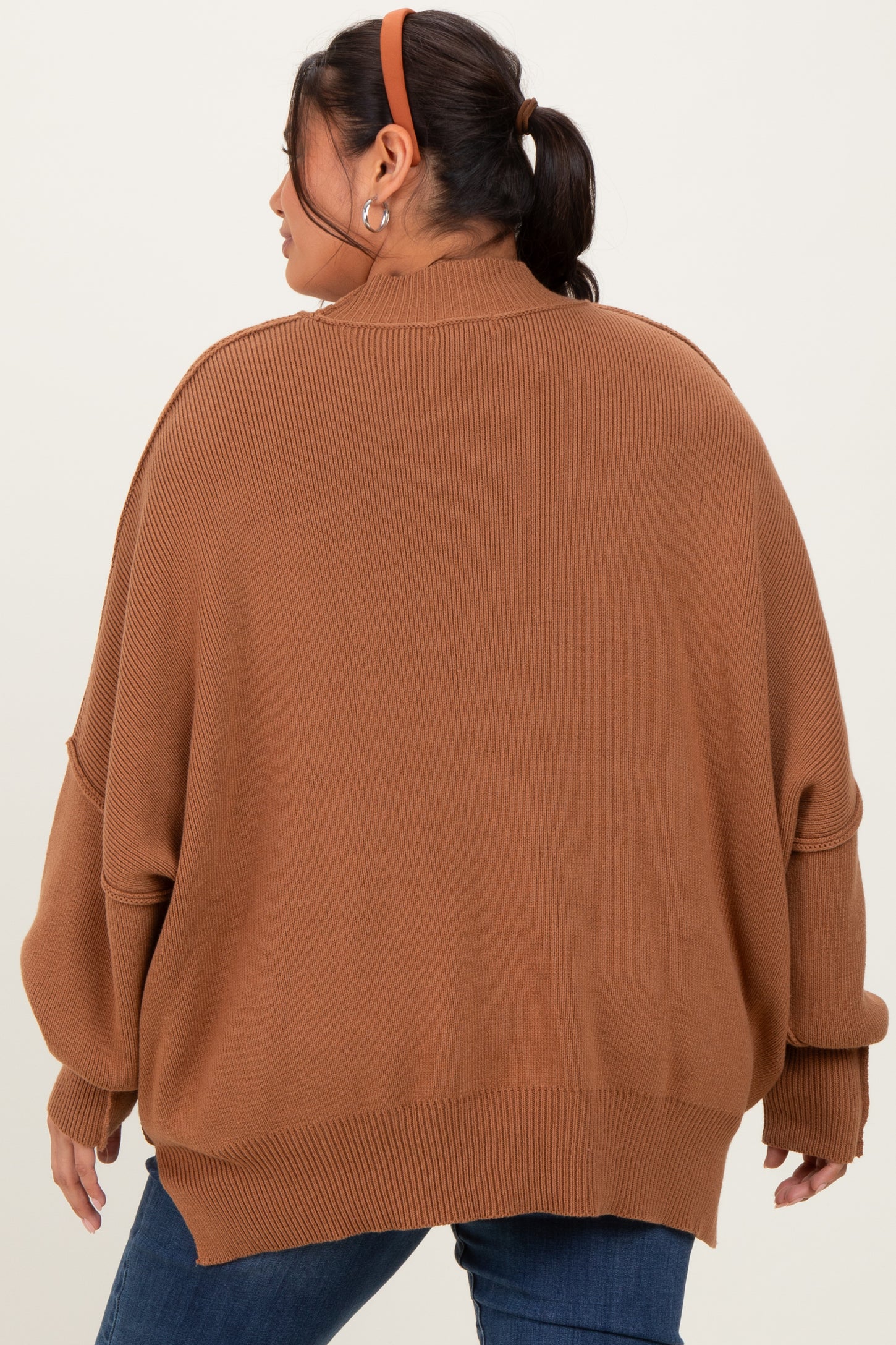 woman wearing a brown oversized sweater with a ribbed texture and dropped shoulder seams, viewed from the back