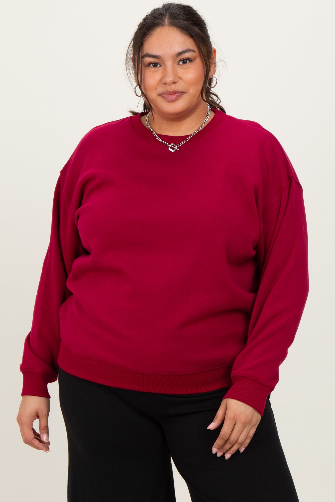 woman wearing a burgundy oversized sweatshirt with drop shoulder seams and relaxed fit