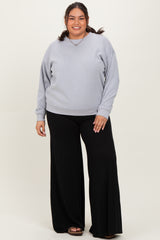 woman wearing a light gray oversized sweatshirt and black wide-leg pants