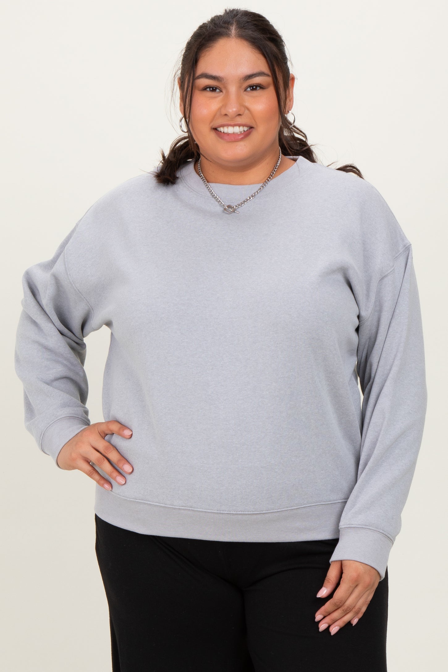 woman wearing a light gray plus-size sweatshirt with a relaxed fit and long sleeves