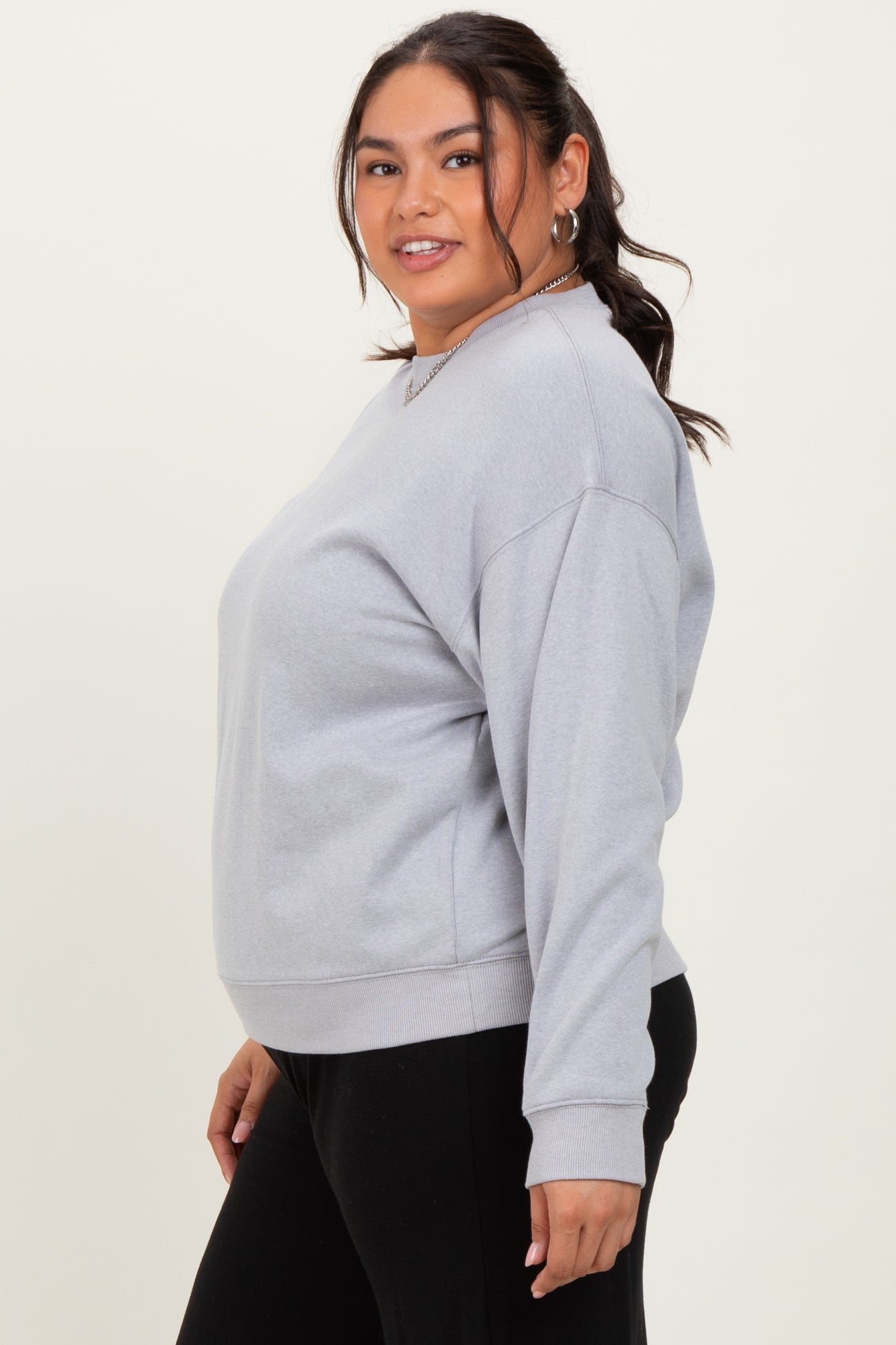 plus size woman wearing a gray oversized sweatshirt with a round neckline and long sleeves