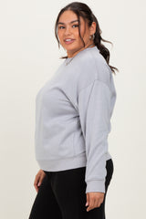 plus size woman wearing a gray oversized sweatshirt with a round neckline and long sleeves