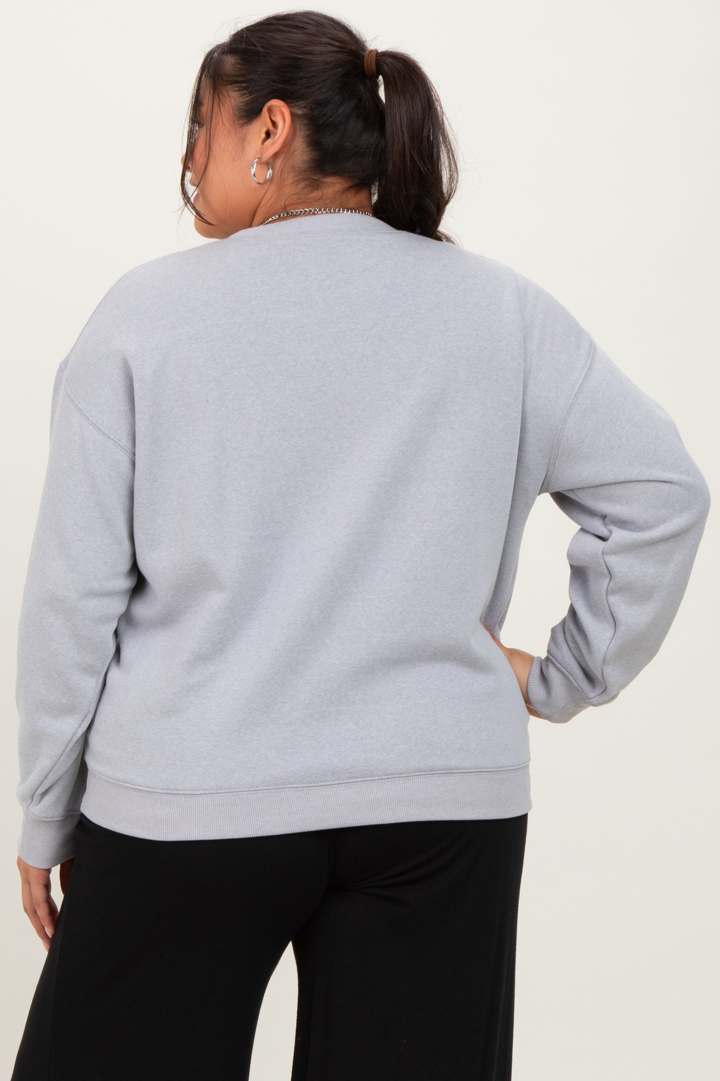 woman wearing a gray oversized sweatshirt from the back with long sleeves and relaxed fit
