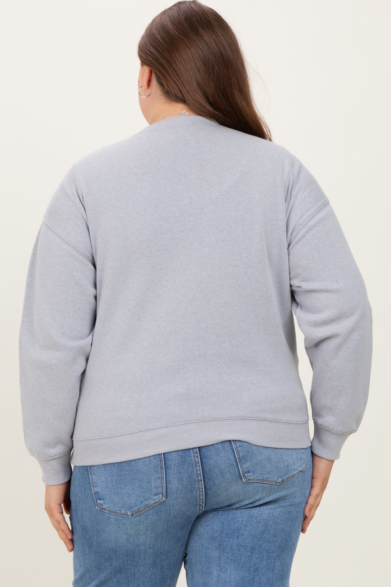 woman wearing a gray oversized sweatshirt with long sleeves and a relaxed fit, viewed from the back