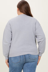 woman wearing a gray oversized sweatshirt with long sleeves and a relaxed fit, viewed from the back