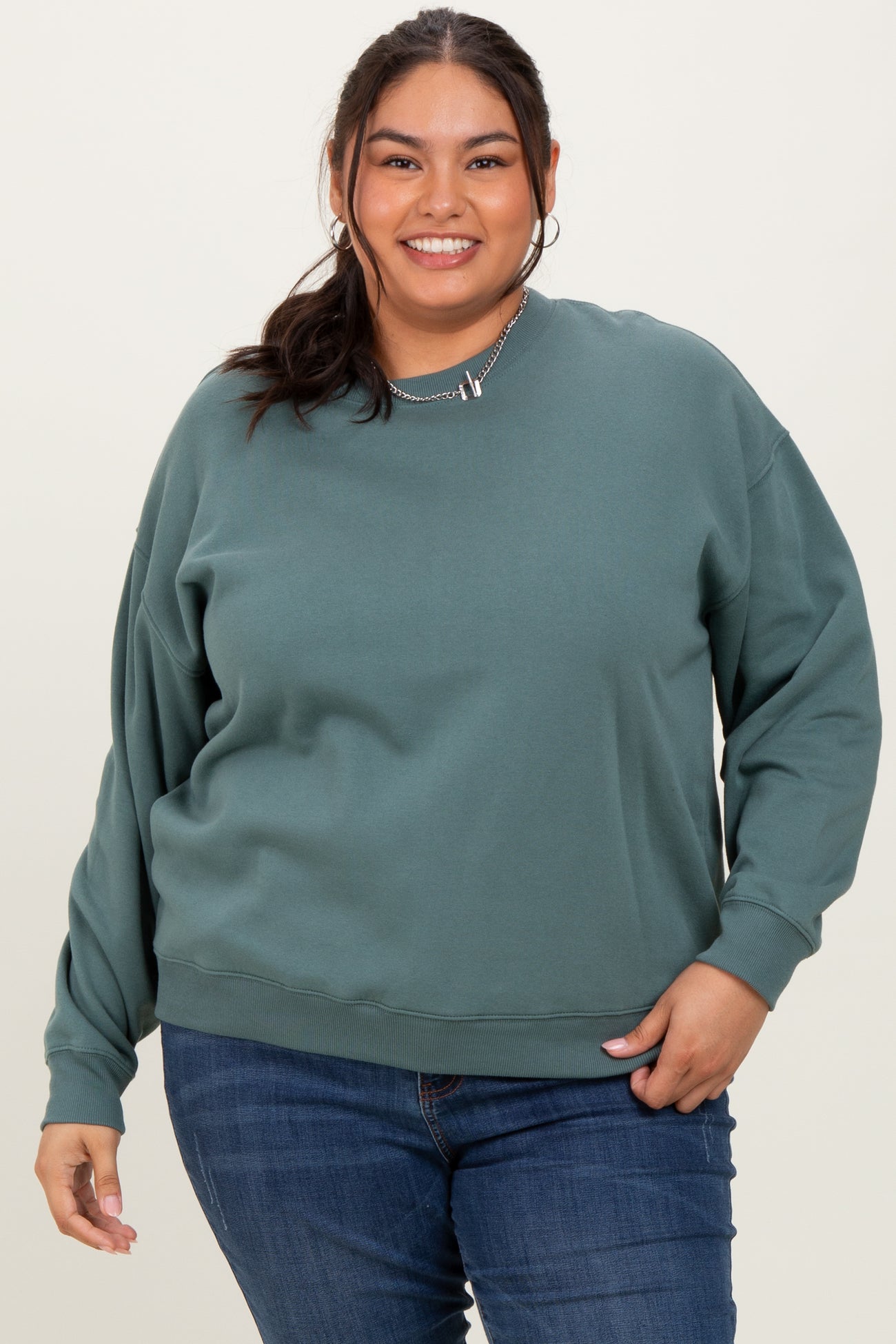 woman wearing a teal oversized sweatshirt with a relaxed fit and long sleeves, paired with blue jeans