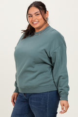 woman wearing a teal oversized sweatshirt with a relaxed fit and long sleeves paired with dark blue jeans