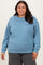 woman wearing a light blue oversized sweatshirt with a round neckline and long sleeves, smiling at the camera