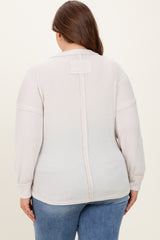 woman wearing a light beige maternity plus long sleeve ribbed top, showing the back view and relaxed fit