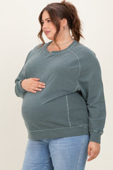 woman wearing a green maternity plus sweatshirt with a relaxed fit and holding her baby bump