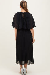 woman wearing a black pleated maternity dress with a cape-style back and ankle-length hem, viewed from the back