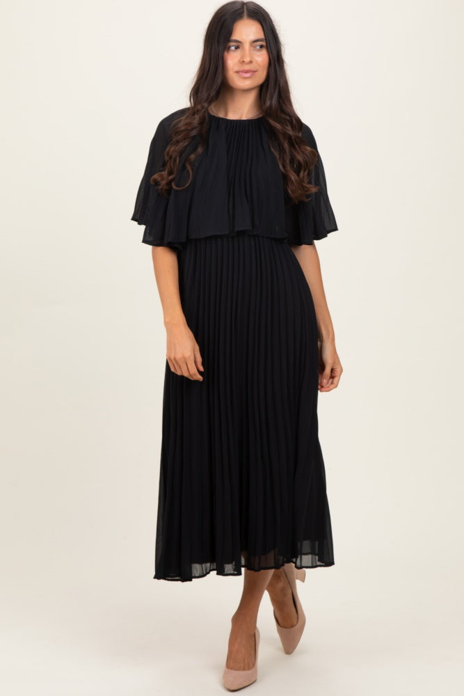 woman wearing a black pleated maxi dress with a cape-style top and nude heels